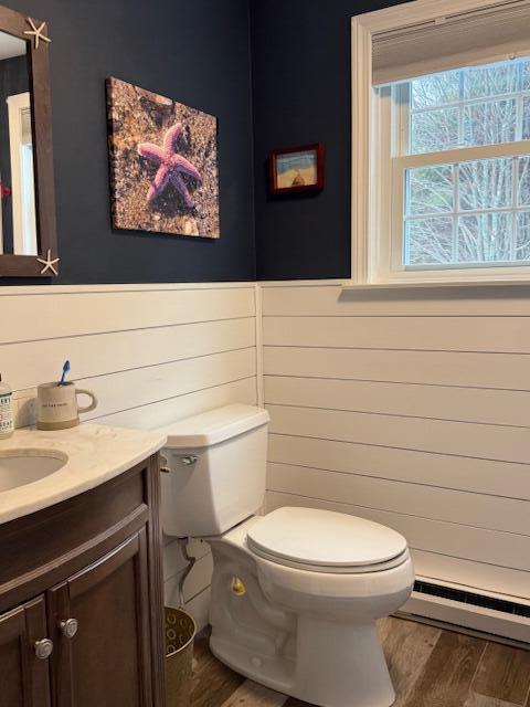 54 Black Smith Rd Unit 13, Wells, ME 04090 - bathroom with vanity, toilet, wood finished floors, and a baseboard radiator