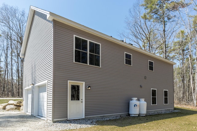 back of property with an attached garage and gravel driveway