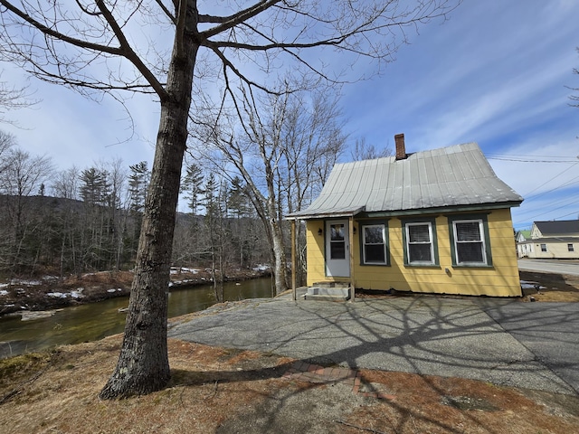 1898 Roxbury Rd, Roxbury, ME 04275 - view of property exterior with a chimney, metal roof, and a water view