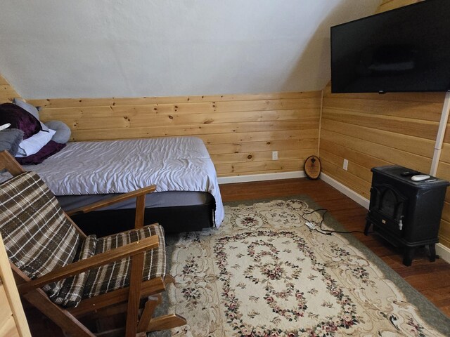 1898 Roxbury Rd, Roxbury, ME 04275 - bedroom with a wood stove, wood finished floors, baseboards, and wooden walls
