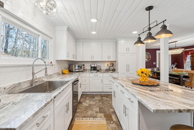 kitchen featuring a healthy amount of sunlight, stone finish floor, recessed lighting, a sink, and dishwasher