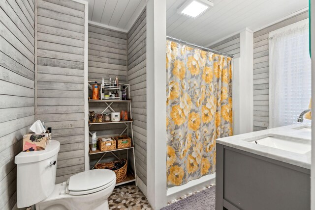 bathroom with wooden walls, toilet, curtained shower, and vanity