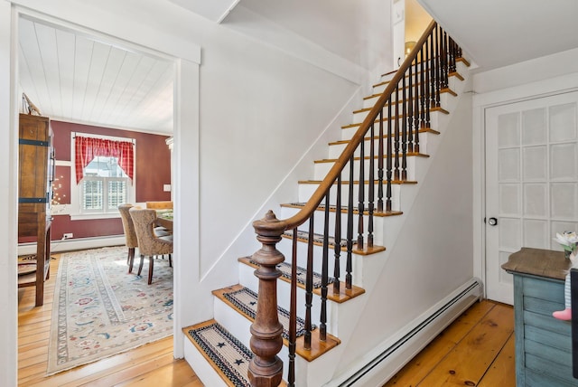 stairway with a baseboard radiator and hardwood / wood-style floors