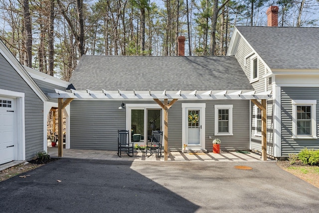exterior space with a patio, roof with shingles, and a chimney