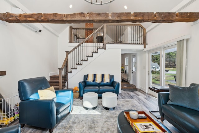 living area featuring a high ceiling, wood finished floors, stairway, and beamed ceiling