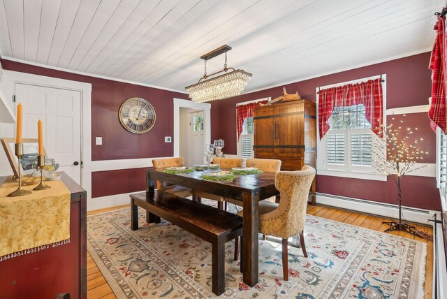 dining room with wood ceiling, baseboard heating, baseboards, wood-type flooring, and ornamental molding