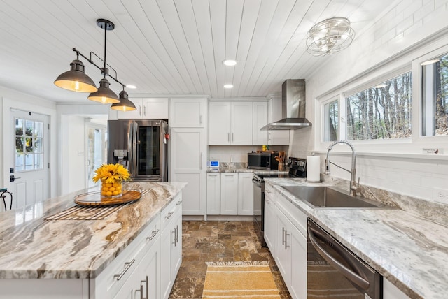 kitchen with wall chimney exhaust hood, white cabinetry, a sink, appliances with stainless steel finishes, and decorative light fixtures