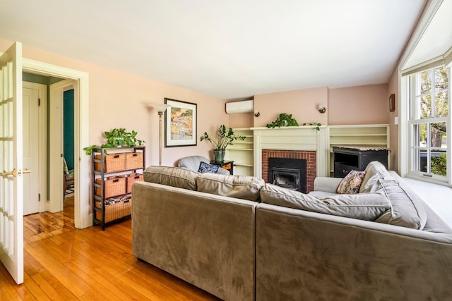 9 Phillips Rd, Falmouth, ME 04105 - living room with a wall mounted AC, light wood-type flooring, and a brick fireplace