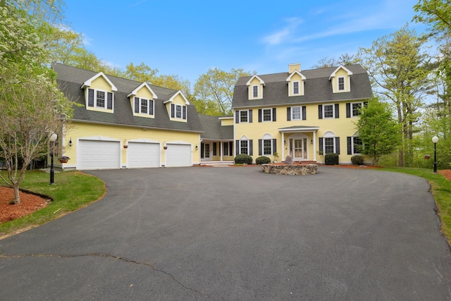 6 Jason Ln, Ogunquit, ME 03907 - view of front of home with driveway, an attached garage, a shingled roof, and a chimney