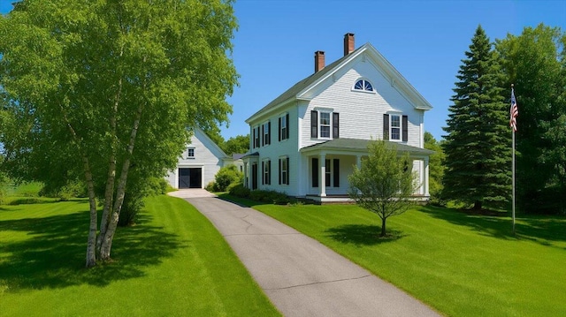view of front of house with covered porch, a chimney, and a front lawn