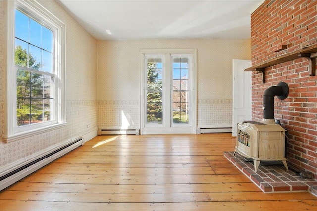 interior space with wood-type flooring, a baseboard heating unit, and wallpapered walls