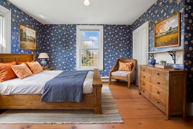 bedroom with light wood-style flooring, baseboard heating, and wallpapered walls