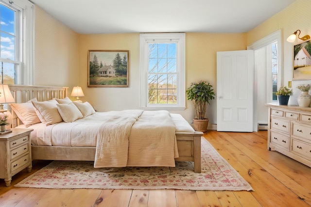 bedroom featuring a baseboard radiator, light wood-type flooring, and wallpapered walls