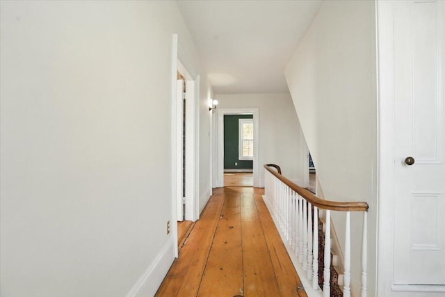 hallway with light wood-type flooring and an upstairs landing