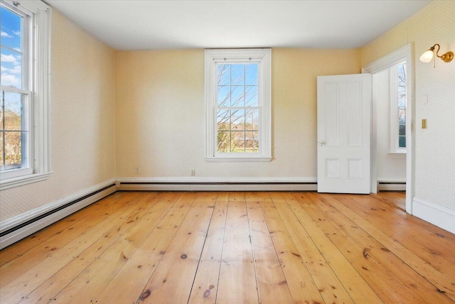 unfurnished bedroom featuring a baseboard heating unit, multiple windows, and hardwood / wood-style floors
