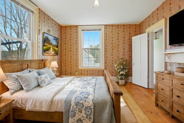 bedroom with wallpapered walls, baseboards, and light wood-style floors