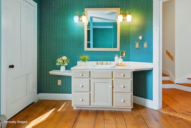 bathroom with wood-type flooring, wallpapered walls, vanity, and a baseboard radiator