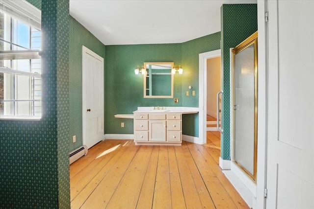 full bath featuring a stall shower, a baseboard heating unit, and hardwood / wood-style flooring