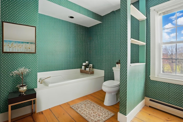 bathroom with wood-type flooring, toilet, wallpapered walls, a baseboard radiator, and a bath