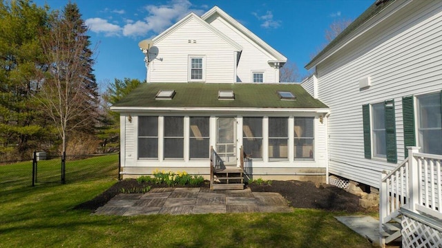 back of property featuring a sunroom, a lawn, and fence