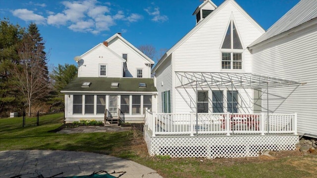 rear view of house featuring a yard, a sunroom, and a deck