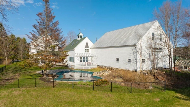 back of house with fence, a lawn, metal roof, and a balcony