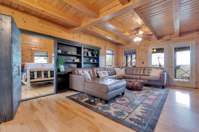 living room with hardwood / wood-style flooring, wooden walls, ceiling fan, beamed ceiling, and wooden ceiling
