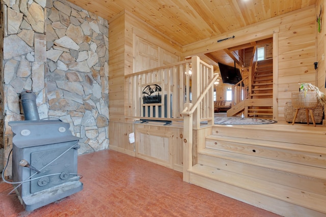 stairs with wood ceiling, wood walls, and a wood stove