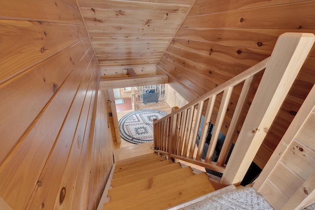 staircase featuring wooden walls, lofted ceiling, and wooden ceiling