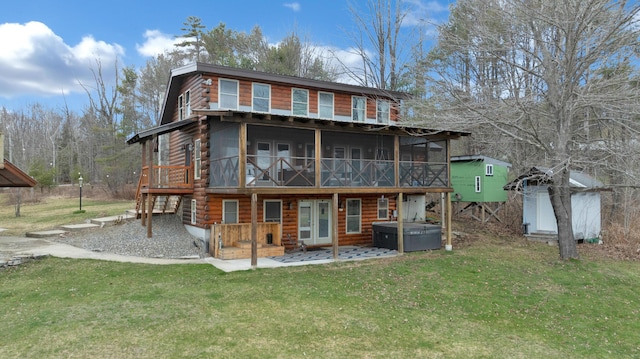 rear view of house featuring a wooden deck, a sunroom, a hot tub, and a yard