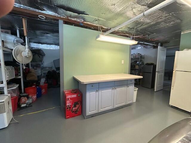 unfinished basement featuring freestanding refrigerator