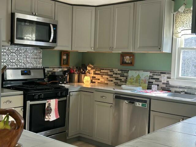 kitchen featuring backsplash, stainless steel appliances, white cabinets, and light countertops