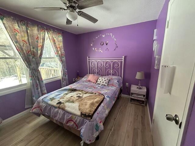 bedroom featuring baseboards, wood finished floors, and ceiling fan
