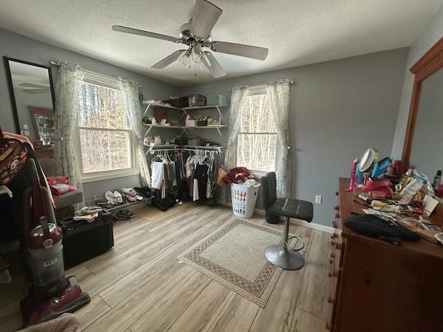 interior space with wood finished floors, a textured ceiling, and ceiling fan