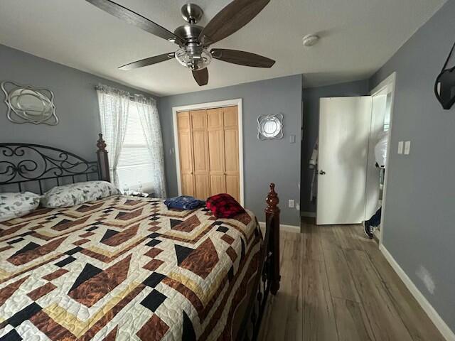 bedroom featuring baseboards, a ceiling fan, wood finished floors, and a closet