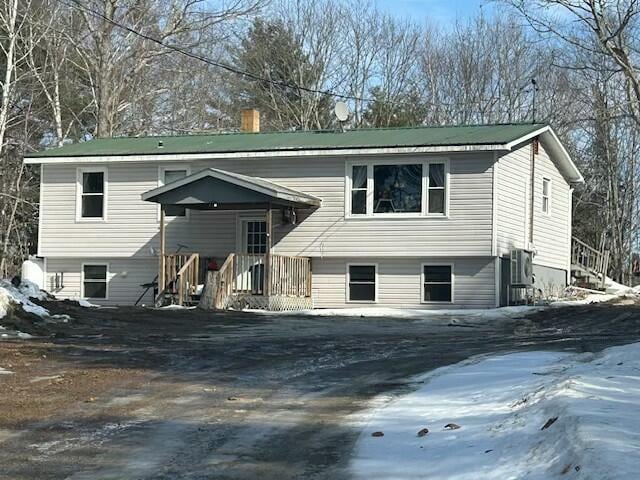 snow covered property featuring a chimney and aphalt driveway