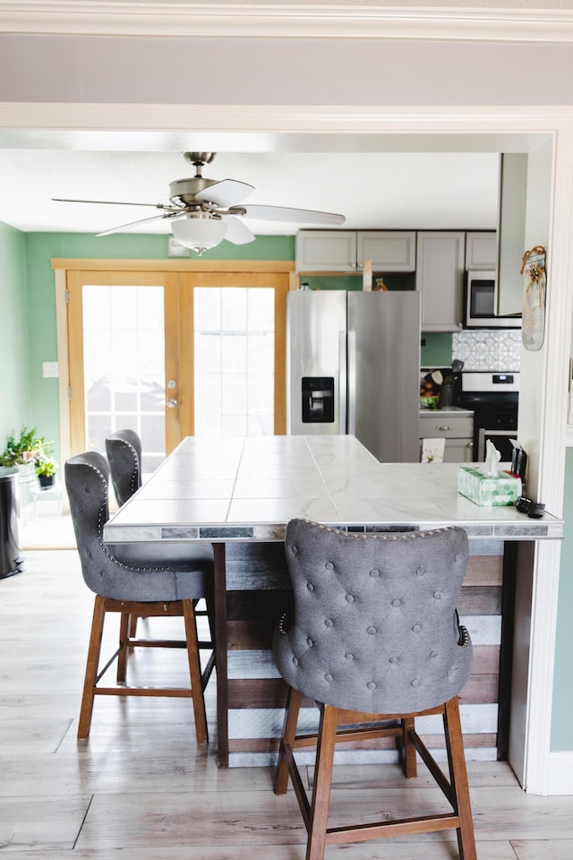 69 Goulds Ridge Rd, Passadumkeag, ME 04475 - kitchen with appliances with stainless steel finishes, gray cabinets, ceiling fan, light wood-type flooring, and a breakfast bar area
