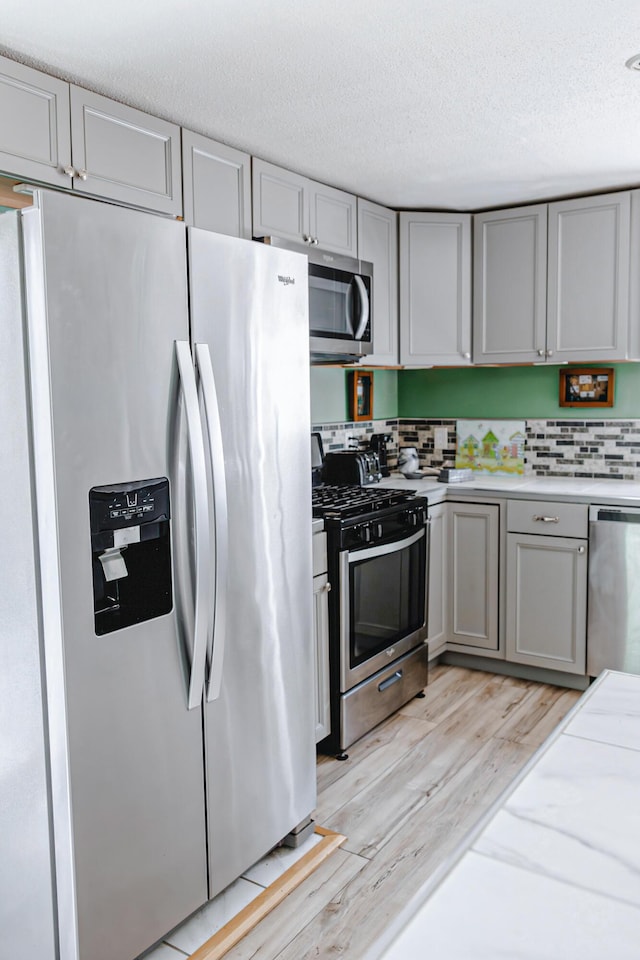 69 Goulds Ridge Rd, Passadumkeag, ME 04475 - kitchen featuring stainless steel appliances, gray cabinetry, light wood-type flooring, light countertops, and a textured ceiling