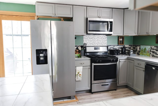 69 Goulds Ridge Rd, Passadumkeag, ME 04475 - kitchen featuring stainless steel appliances, gray cabinetry, light countertops, tasteful backsplash, and light wood-type flooring
