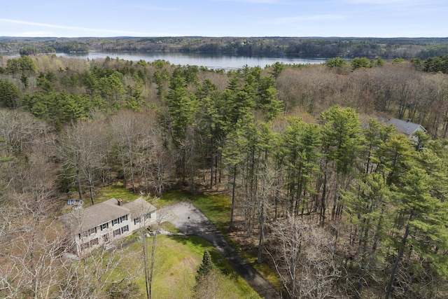 aerial view of property and surrounding area featuring a heavily wooded area and a nearby body of water