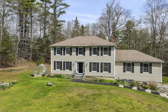 colonial inspired home with an exterior structure, a chimney, a front lawn, and an outdoor structure