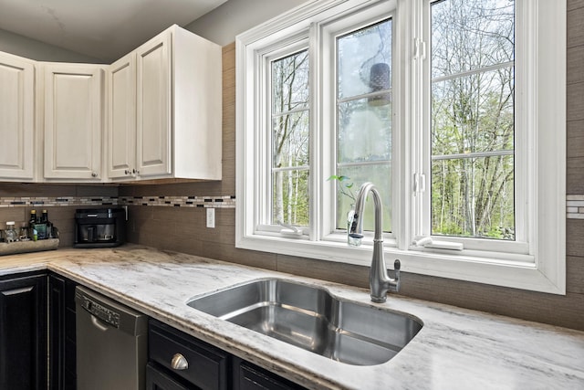 kitchen featuring dishwasher, a sink, healthy amount of natural light, and tasteful backsplash