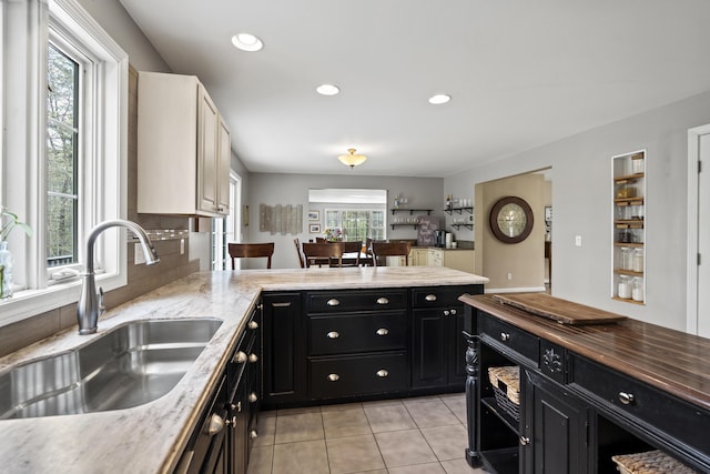 kitchen featuring a sink, dark cabinets, light tile patterned floors, a peninsula, and recessed lighting