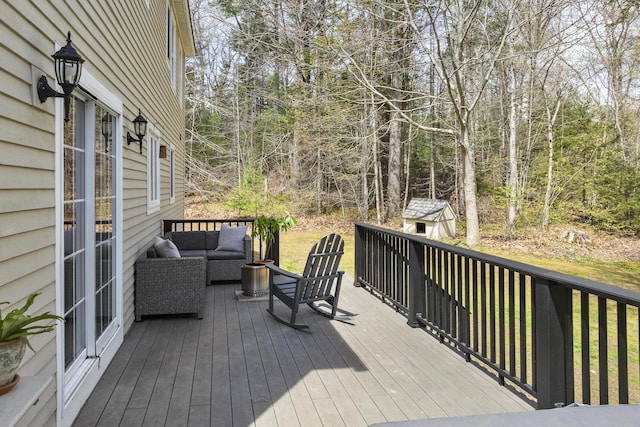 wooden terrace with a storage shed, an outdoor living space, an outbuilding, and a forest view