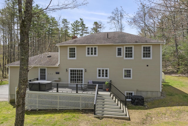 rear view of house with a yard, a wooden deck, a chimney, and roof with shingles