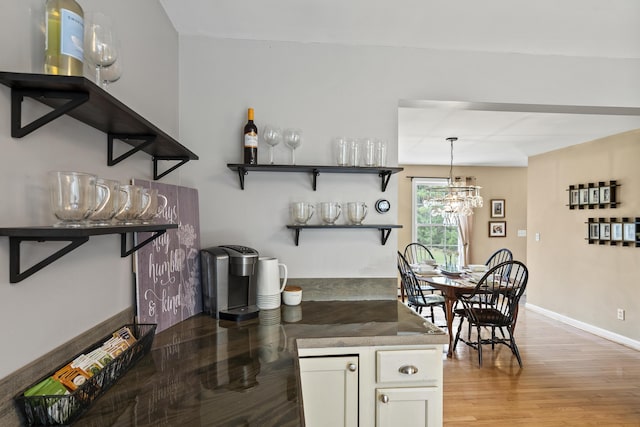 kitchen featuring white cabinets, light wood-type flooring, open shelves, baseboards, and dark countertops