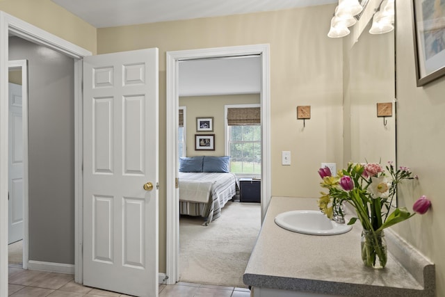bathroom featuring tile patterned flooring, vanity, a chandelier, and baseboards