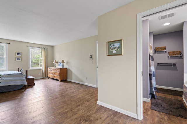 bedroom featuring wood finished floors, baseboards, and a spacious closet
