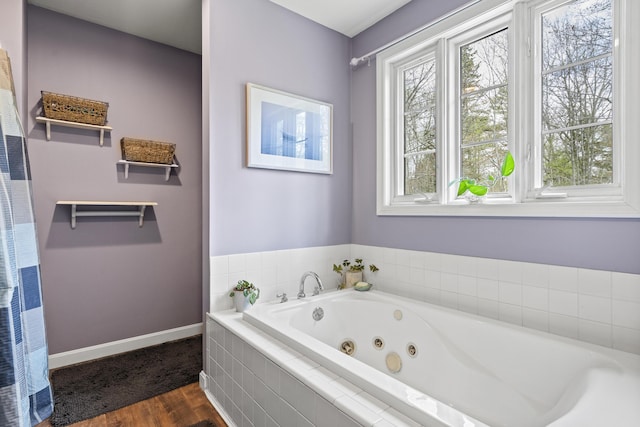 full bath with wood finished floors, baseboards, a tub with jets, and a heating unit