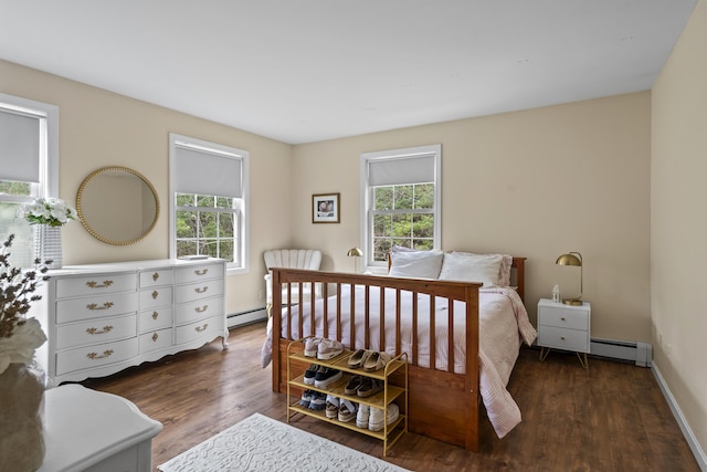 bedroom with baseboard heating, multiple windows, wood finished floors, and a baseboard heating unit